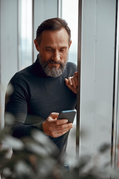 Smiling man holding mobile phone while texting