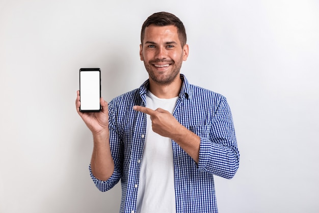 Smiling man holding a smartphone and pointing to screen 