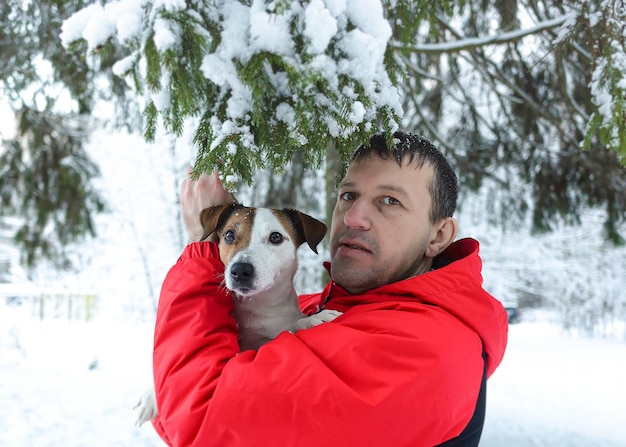 A smiling man holds a purebred dog in his arms Jack Russell terrier Pets in winter