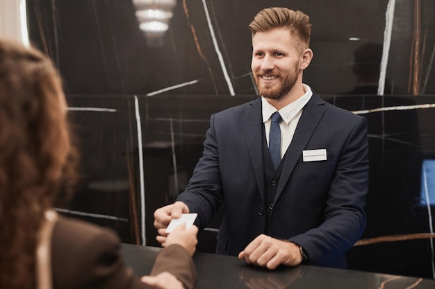 Photo smiling man at hotel reception desk welcoming guest