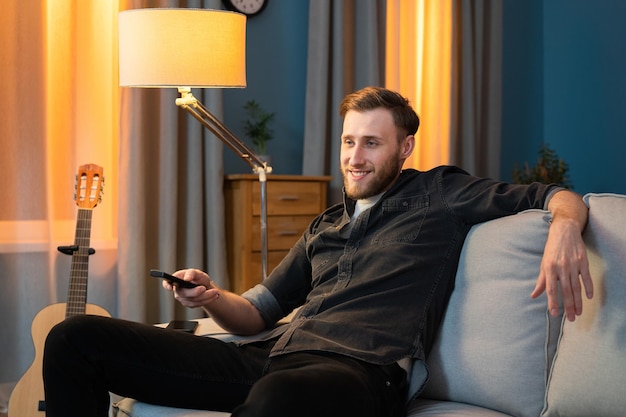 A smiling man is relaxing after work in his homey cozy living room in the evening