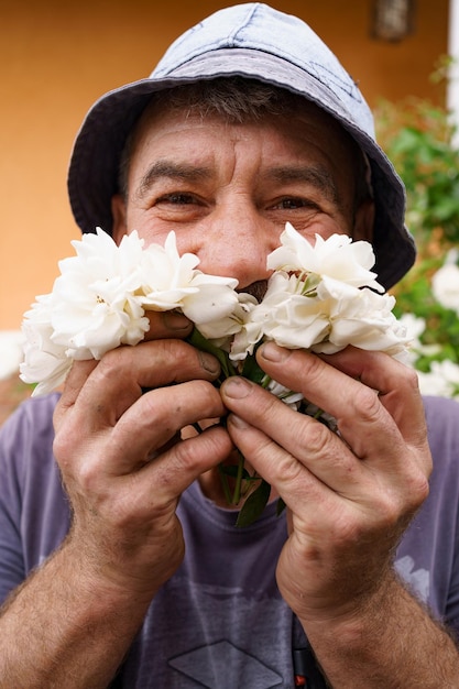 Smiling man portrait enjoying aroma of white roses