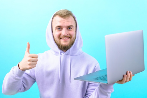 Smiling man showing his thumb up and holding a laptop on the blue background Casual Hand Lifestyle Confidence Connection Gesturing Entrepreneur Expertise Expression Employee Joy Good