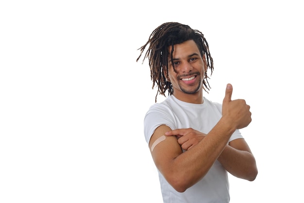 Smiling man showing thumb up after being vaccinated against Covid-19 virus over an isolated background. Healthcare and medicine concept.