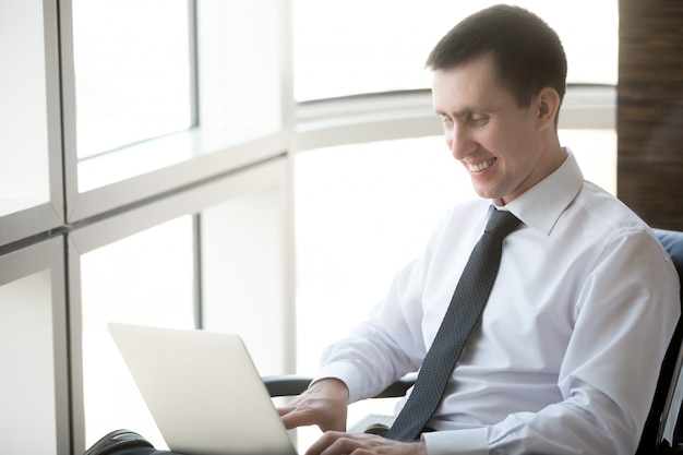 Smiling man typing on a laptop