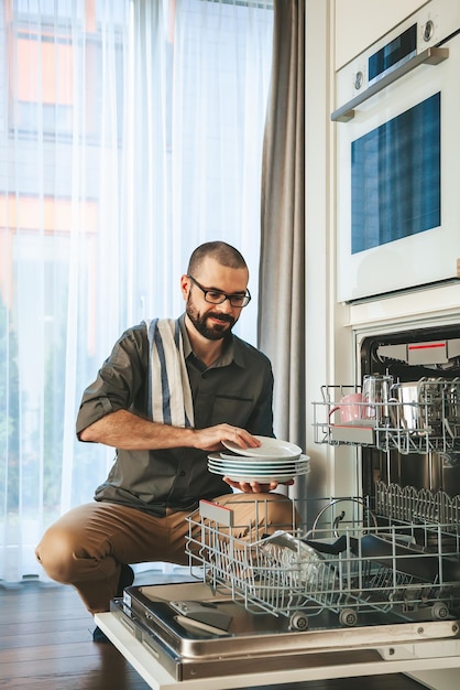 Smiling man unloading dishwasher