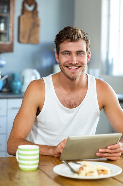 Smiling man using tablet PC at breakfast table