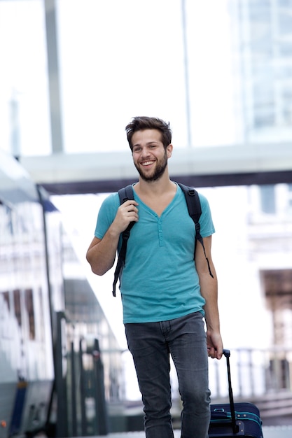 Smiling man walking with bags at train station