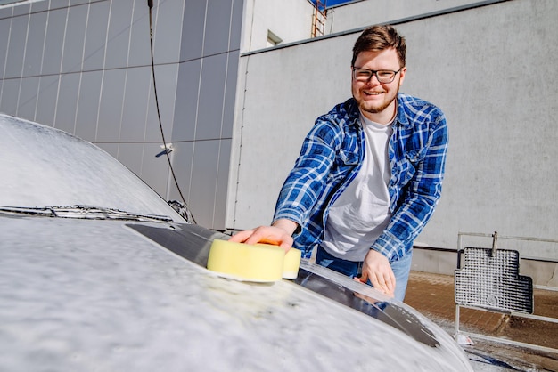 Smiling man washing his car selfservice carwash concept