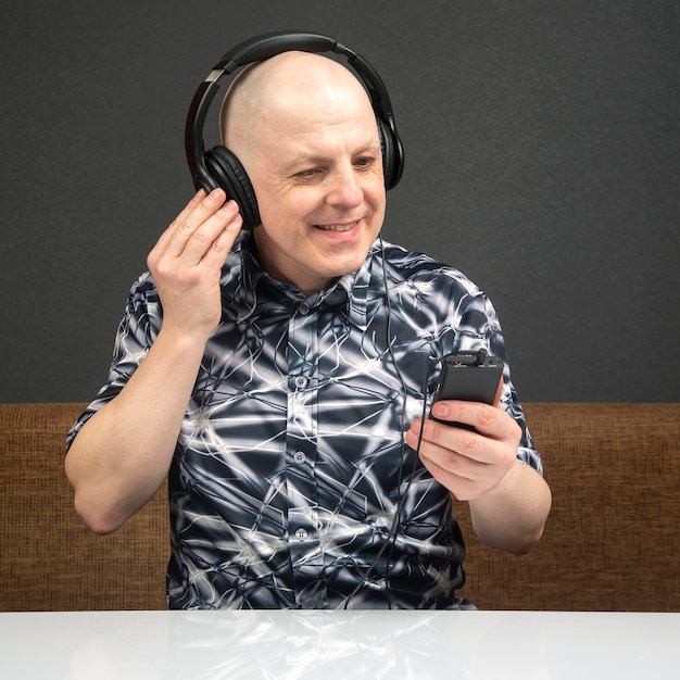 Smiling man with headphones and digital portable player in hand relaxes while listening to his favorite music