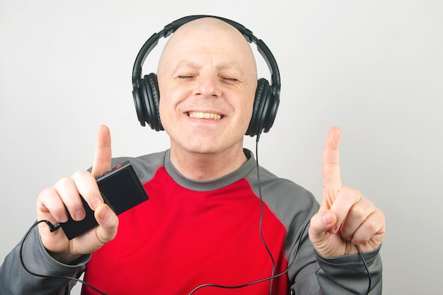 Smiling man with headphones and digital portable player in hand relaxes while listening to his favorite music