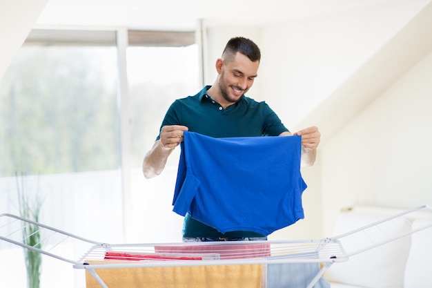 Photo smiling man with laundry and drying rack at home