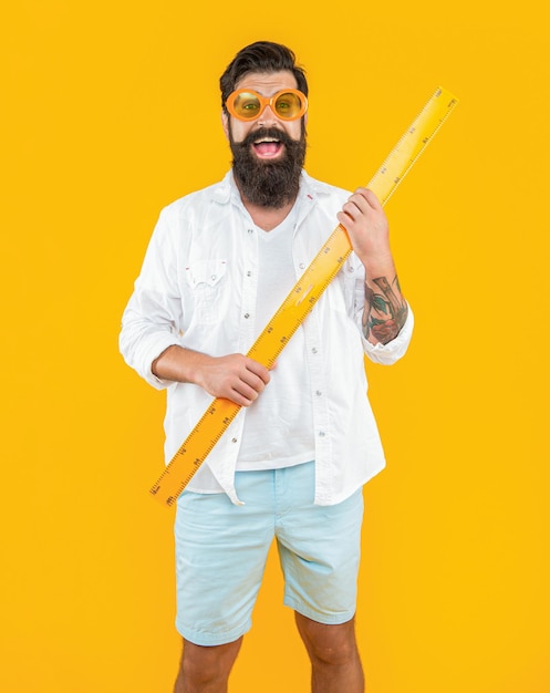 Smiling man with measuring ruler isolated on yellow man with measuring ruler in studio