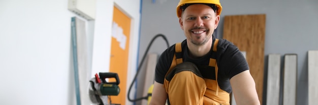 Smiling master in hard hat holds laminate board