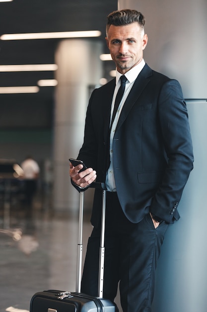 Smiling mature businessman holding mobile phone