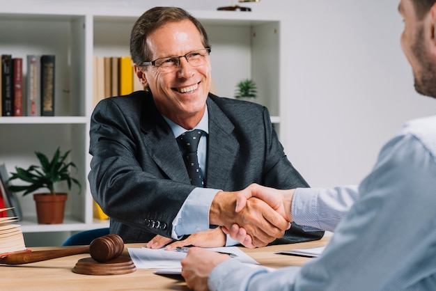 Smiling mature businessman shaking hands with client in the courtroom