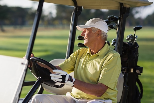 Smiling mature man driving golf buggy