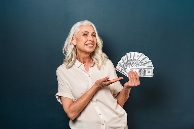 Smiling mature old woman showing money holding in hands.