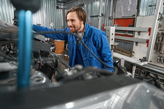 Smiling mechanic holding special tool for auto repair