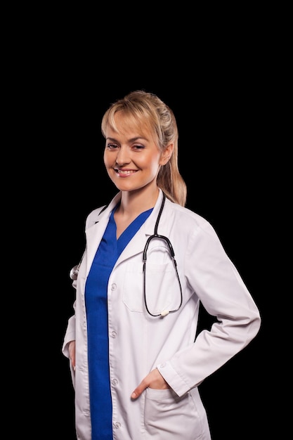 Smiling medical doctor woman with stethoscope. Isolated over black background