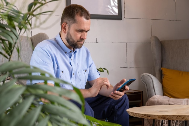 Smiling middle aged businessman freelancer using mobile phone checking social media feed or message chat while sitting in cafe Online digital communication rest after a hard day's work