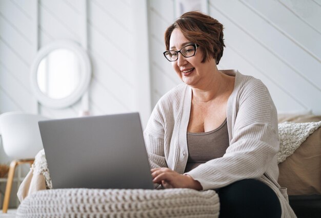 Smiling middle aged plus size woman working on laptop from home