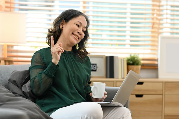 Smiling middle aged woman making video call having virtual chat on laptop from home Retirement lifestyle concept