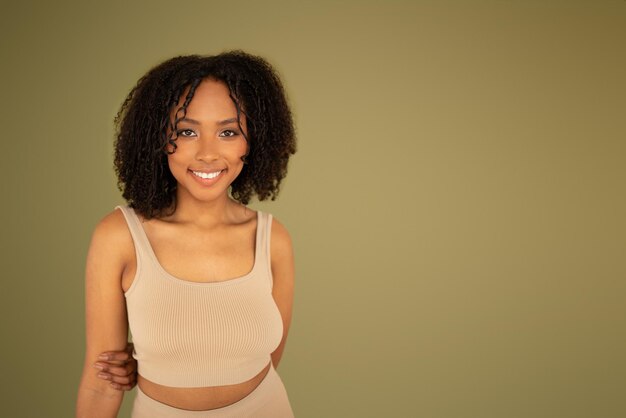 Smiling millennial curly african american lady in sportswear looking at camera