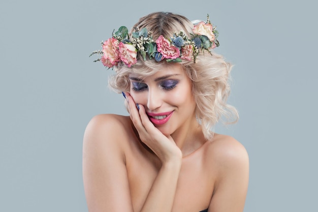 Smiling model in flowers Beautiful young woman with short blonde curly hair and bright makeup