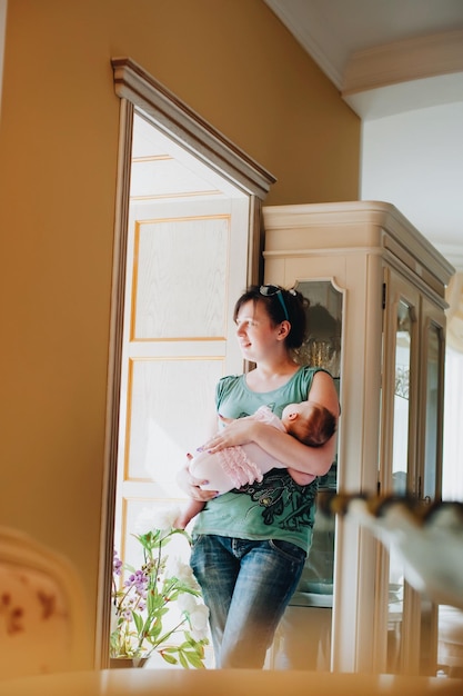 Photo smiling mother carrying daughter while standing at home