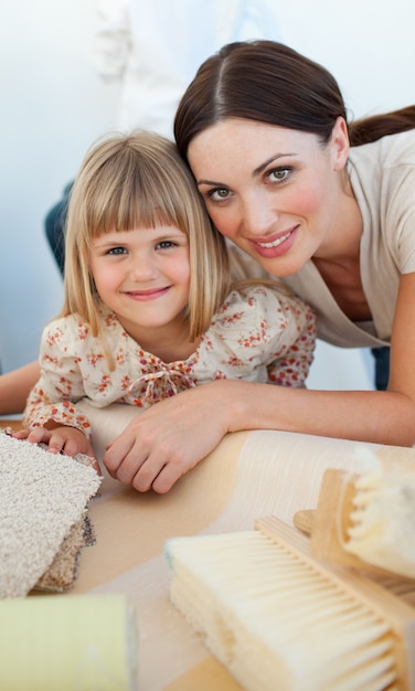 Smiling mother and her daughter decorating a room 