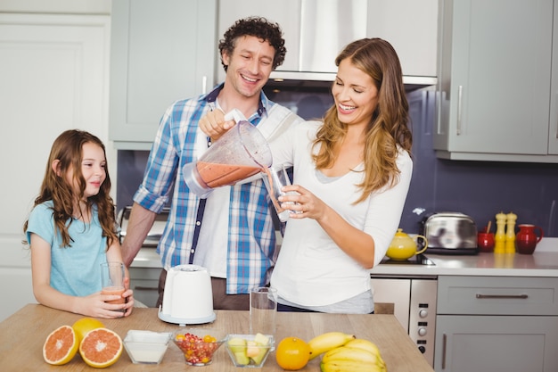 Smiling mother pouring fruit juice in a glass with family 