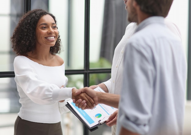 Smiling multiethnic businesspeople shaking hand in office