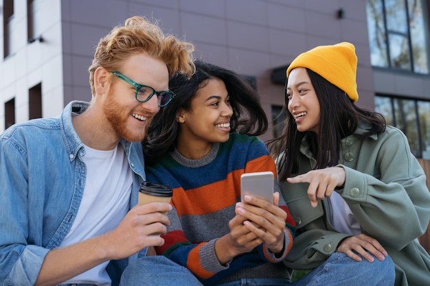 Smiling multiracial friends meeting using mobile phone communication together on the street