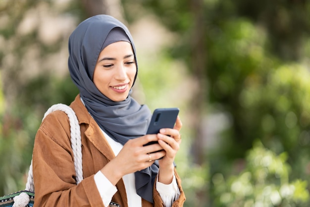 Smiling muslim woman using a mobile Close up