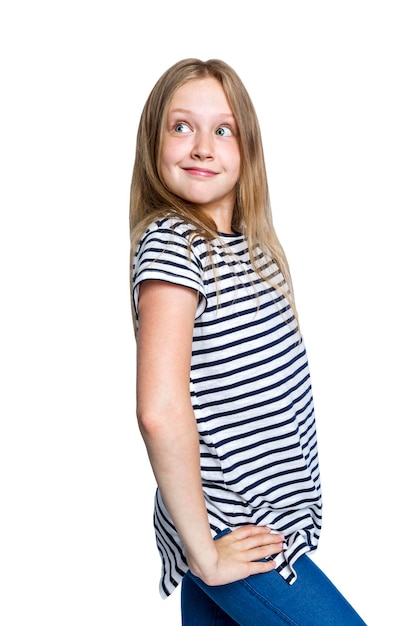 Smiling mysterious redhaired girl is standing A teenager in jeans and a striped tshirt Positive happiness and good mood Isolated on white background Vertical