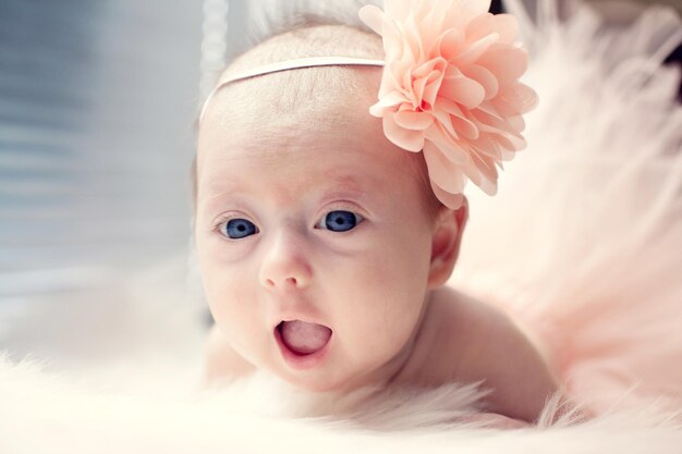 Smiling newborn baby girl with a flower in her hair