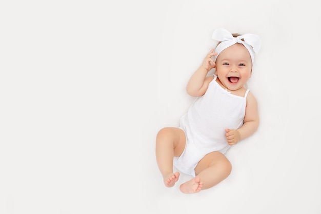 Smiling newborn baby on a white bed at home, the concept of a happy, healthy baby