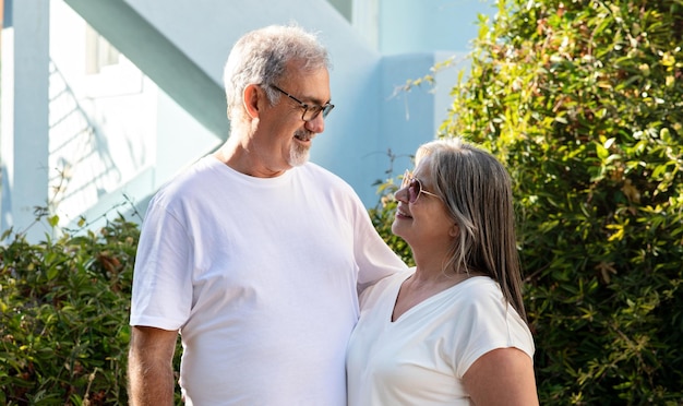 Smiling old european husband and wife in white tshirts hugging enjoy spare time outdoors