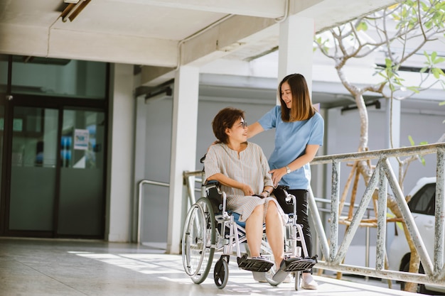 Smiling physiotherapist taking care of the happy senior patient in wheelchair