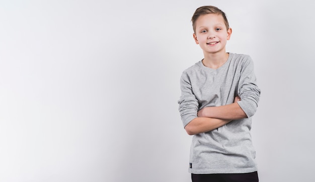 Smiling portrait of a boy with his arms crossed looking to camera against white background