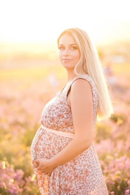 Smiling pregant woman in lavender flowers meadow