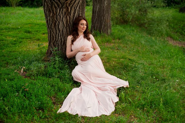 Smiling pregnant woman 25-29 year old resting by the lake. Motherhood. Maternity