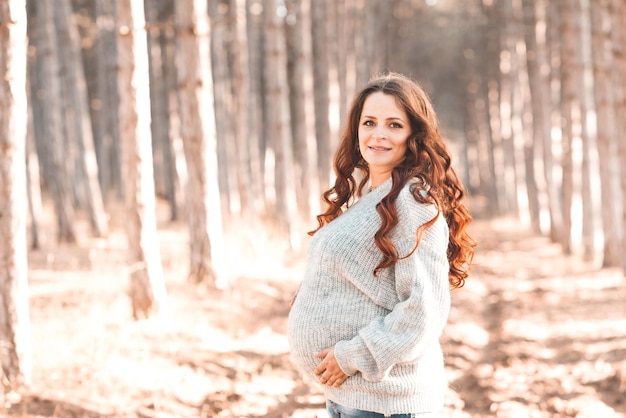 Smiling pregnant woman wear casual clothes posing in park outdoor