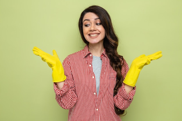 Smiling pretty caucasian cleaner woman with rubber gloves holding hands open 