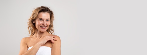 Photo smiling pretty middle aged woman wrapped in bath towel