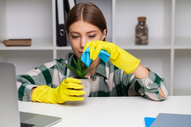 Smiling pretty woman cleans the office at her home