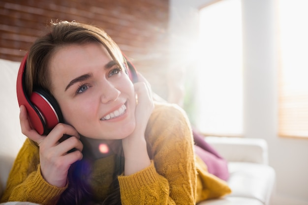 Smiling pretty woman listening music lying on the couch in the living room