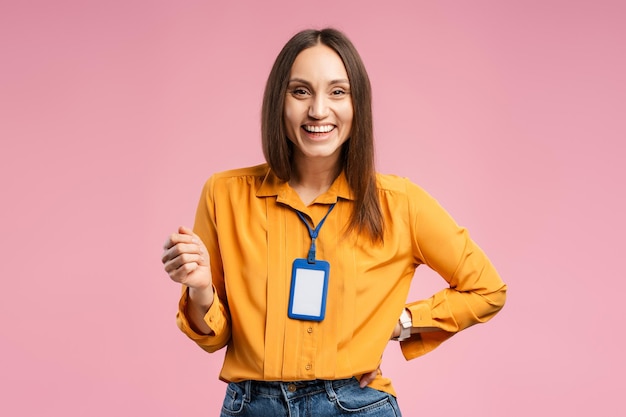 Photo smiling pretty young woman posing in studio with accreditation card on the neck