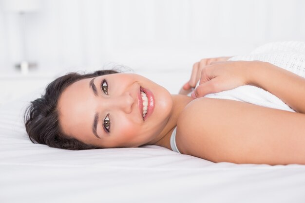 Smiling pretty young woman relaxing in bed